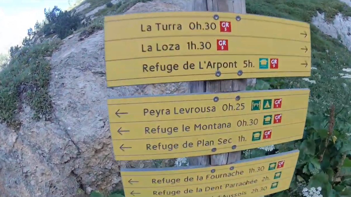 A mountain signpost giving walking times to the refuges beyond, waymarked for the GR5.