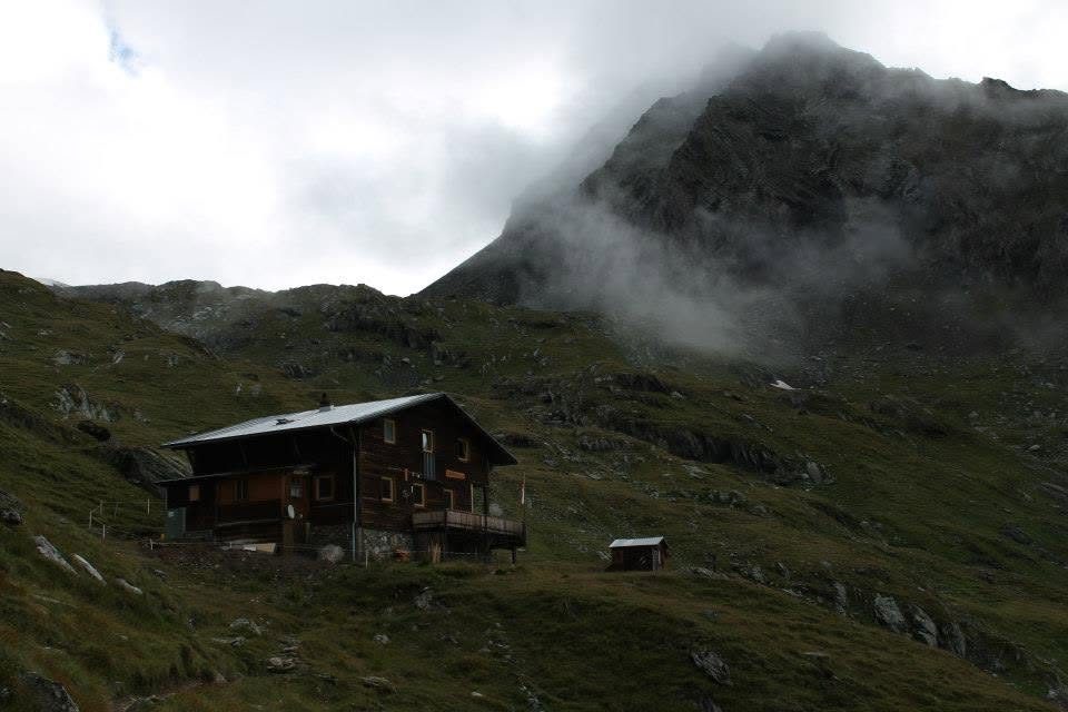 A hut under low cloud, the ridge behind it lost in the weather.